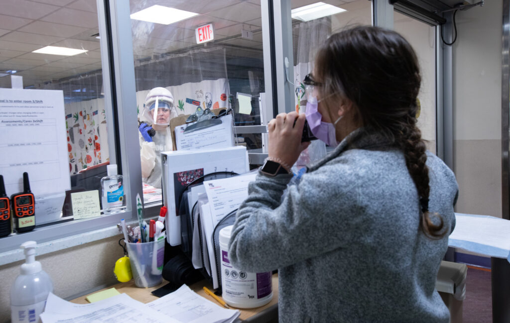 Two nurses in the pediatric intensive care unit at Children’s National Hospital in Washington, D.C., communicate via walkie-talkie, as one helps on floor with COVID-19 patients and her colleague stands by to assist. Two nurses in the pediatric intensive care unit at Children's National Hospital in Washington, D.C., communicate via walkie-talkie, as one helps on floor with COVID-19 patients and her colleague stands by to assist.