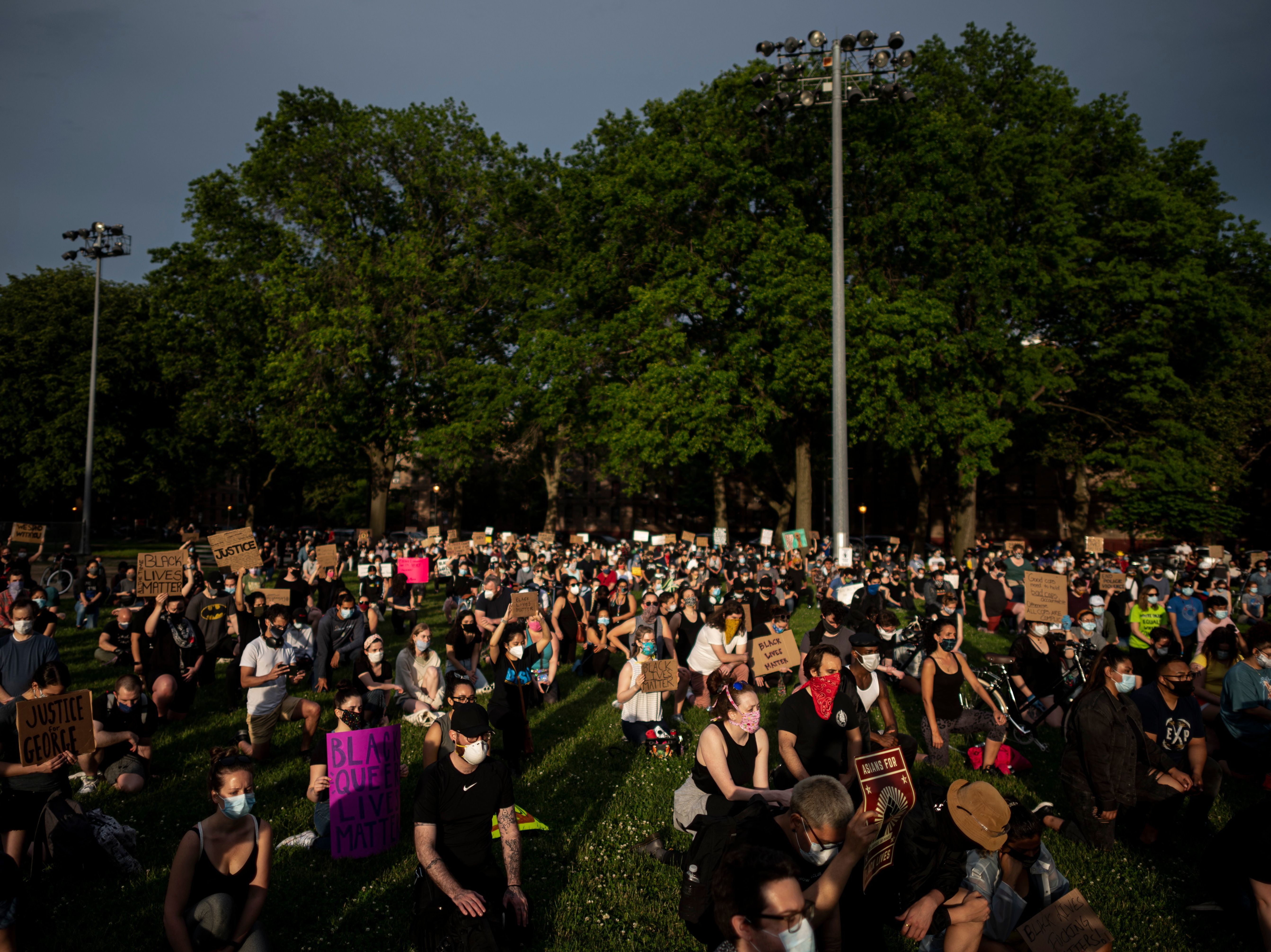 Protesters kneel down and hold placards as they take part in a "Black Lives Matter" vigil Wednesday in the Queens borough of New York City.