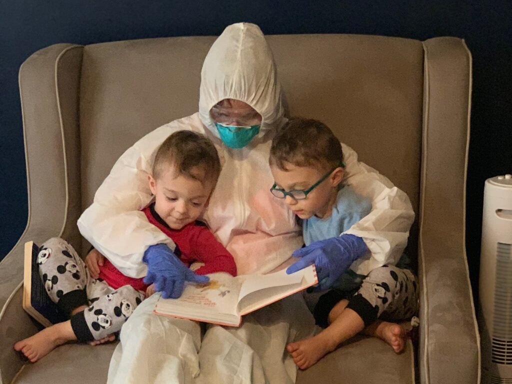 Dr. Lauren Jenkins reads to her twin sons, Pierce and Ashton, while wearing her “hazmat” suit. Because lung cancer has compromised her husband’s immune system, Jenkins moved out of her home and visited in the suit as a precaution. Dr. Lauren Jenkins reads to her twin sons, Pierce and Ashton, while wearing her