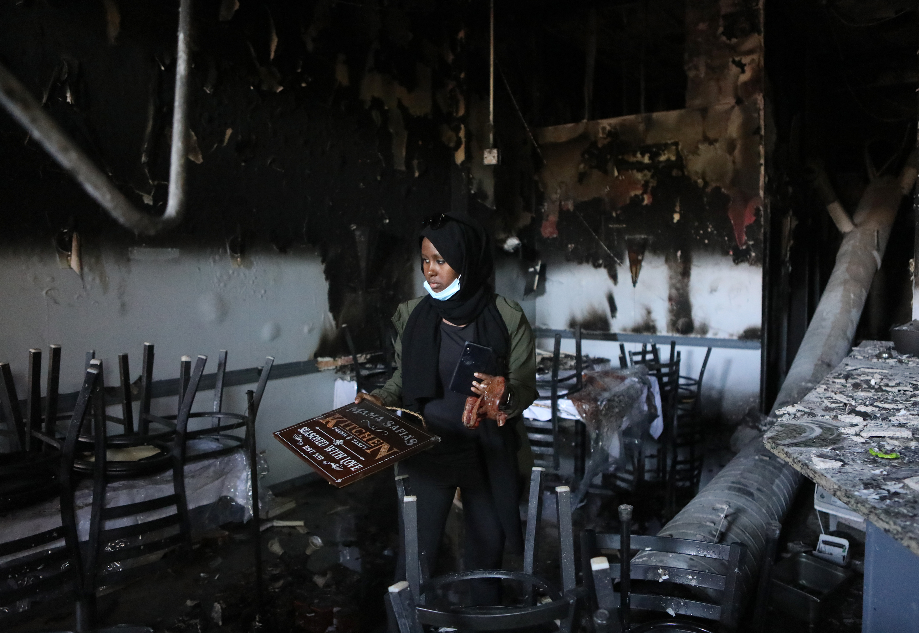 Saida Hassan looks over the remains of her mother's restaurant, Mama Safia's Kitchen, on Saturday. She doesn't want destruction, but says, "people are crying for help."