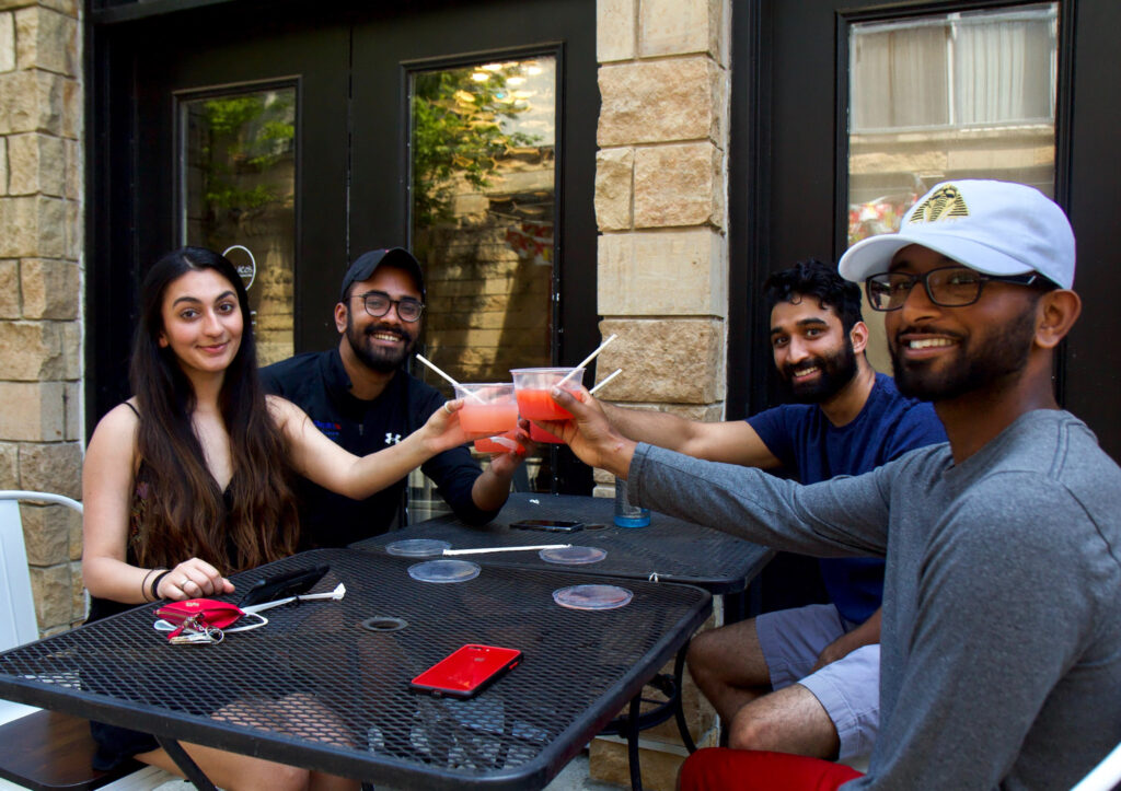 Rayyan Aziz (front left), Joel James (back left), Ravi Patel (back right) and Sean Shaji (front right) toast with margaritas at Set NoLibs outdoor seating. Today is the first day outdoor dining is allowed since coronavirus shutdowns. (Kimberly Paynter/WHYY)