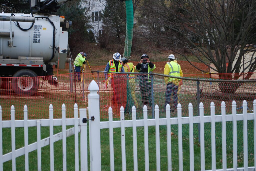 2018-04-02-16.41.271-1920×1285 In this May 2018 photo, workers and contractors for Sunoco Pipeline investigate sink holes behind homes at Lisa Drive, West Whiteland Township, Chester County where the company has been drilling for construction of the Mariner East 2 and 2X pipelines. In the photo, a security guard is taking a picture of the reporter. (Jon Hurdle / StateImpact PA)