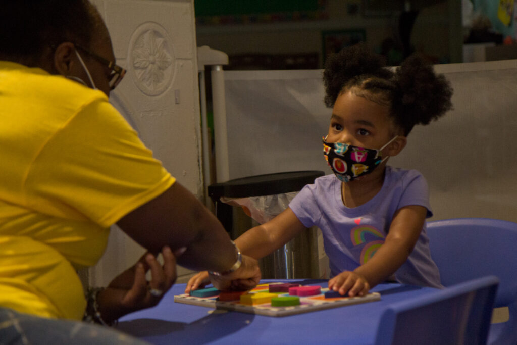 2020 7 10 k paynter daycare masks-7 Kimrenee Patterson works on a puzzle, with Peyton, 2, at Patterson’s daycare in Philadelphia. (Kimberly Paynter/WHYY)