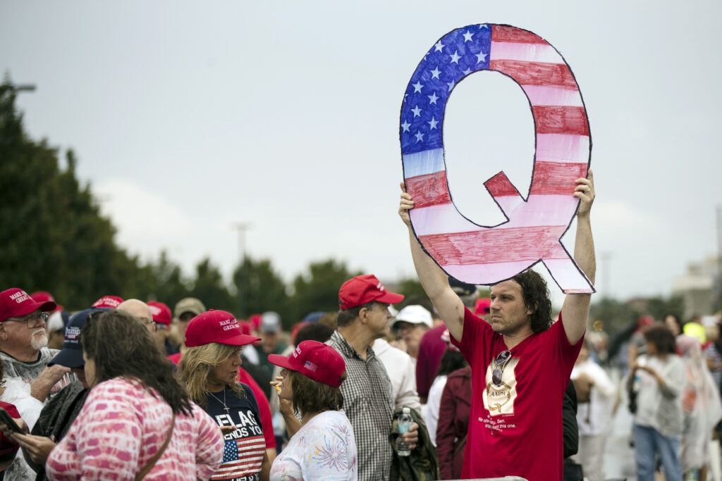 FILE - In this Aug. 2, 2018, file photo, David Reinert holding a Q sign waits in line with others to enter a campaign rally with President Donald Trump in Wilkes-Barre, Pa. A far-right conspiracy theory forged in a dark corner of the internet is creeping into the mainstream political arena. It's called QAnon, and it centers on the baseless belief that President Donald Trump is waging a secret campaign against enemies in the “deep state.”  (AP Photo/Matt Rourke, File)