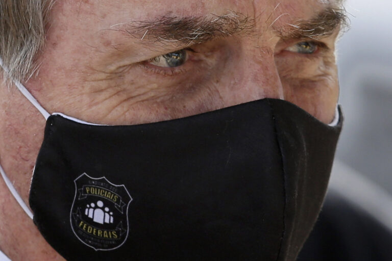 FILE - In this May 26, 2020 file photo, Brazil's President Jair Bolsonaro, wearing a face mask with a logo of the Federal Police, leaves his official residence of Alvorada Palace in Brasilia, Brazil.  (AP Photo/Eraldo Peres, FIle)