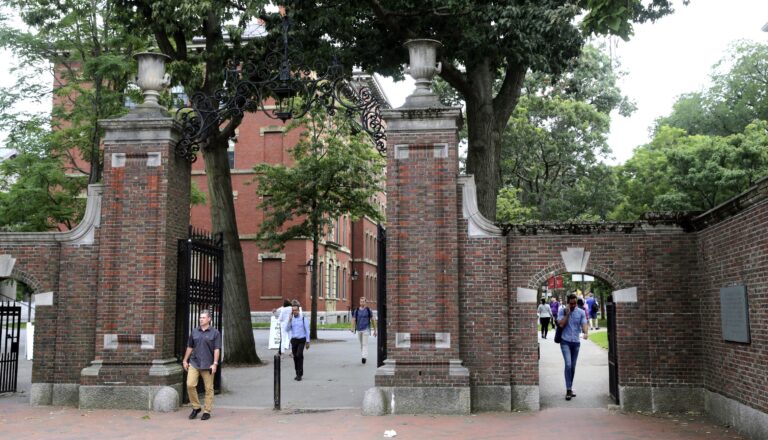 FILE - In this Aug. 13, 2019, file photo, pedestrians walk through the gates of Harvard Yard at Harvard University in Cambridge, Mass. Harvard and the Massachusetts Institute of Technology filed a federal lawsuit Wednesday, July 8, 2020, challenging the Trump administration’s decision to bar international students from staying in the U.S. if they take classes entirely online this fall. Some institutions, including Harvard, have announced that all instruction will be offered remotely in the fall during the ongoing coronavirus pandemic. (AP Photo/Charles Krupa, File)