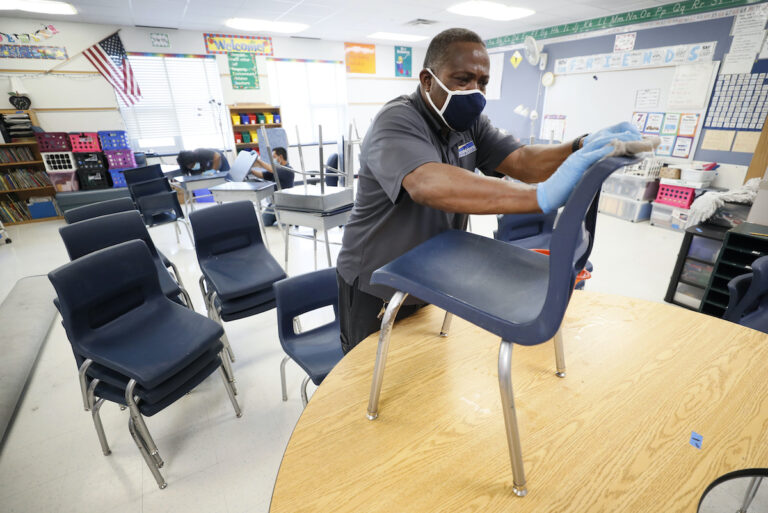 Custodian Tracy Harris cleans chairs in a classroom at Brubaker Elementary School, Wednesday, July 8, 2020, in Des Moines, Iowa. (AP Photo/Charlie Neibergall)