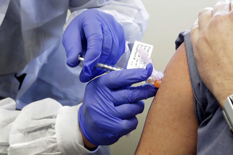 In this March 16, 2020, file photo, a patient receives a shot in the first-stage safety study clinical trial of a potential vaccine for COVID-19, the disease caused by the new coronavirus, at the Kaiser Permanente Washington Health Research Institute in Seattle. (AP Photo/Ted S. Warren)