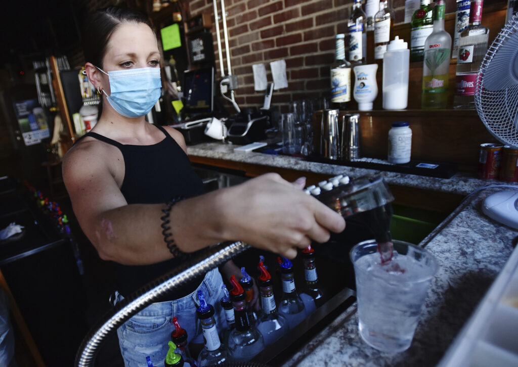 Bartender Kelsey Drozda makes a drink behind the bar at the Riverside Caf