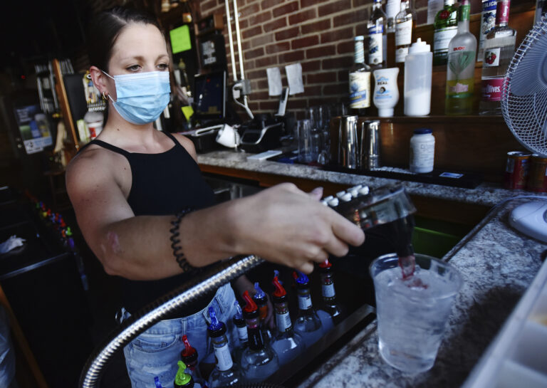 Bartender Kelsey Drozda makes a drink behind the bar at the Riverside Caf