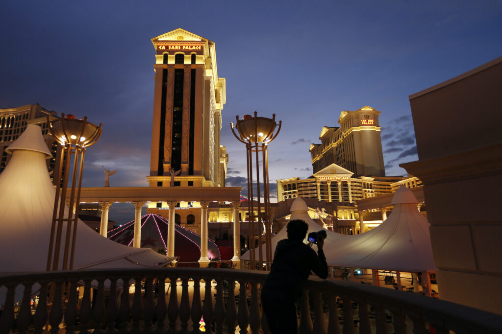 Eldorado Resorts-Caesars Entertainment In this Jan. 12, 2015, file photo, a man takes pictures of Caesars Palace hotel and casino in Las Vegas. (AP Photo/John Locher)