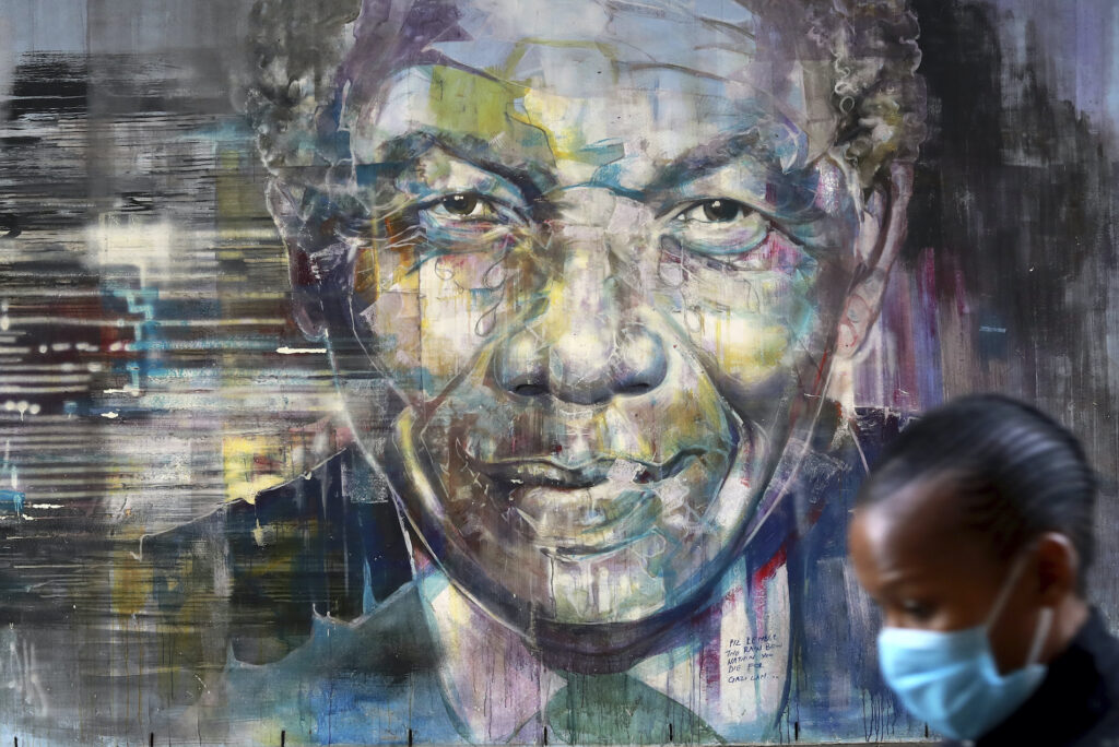South Africa International Mandela Day A masked woman walks past a mural of former President Nelson Mandela in Cape Town, South Africa, Saturday July 18, 2020 as the country celebrates International Mandela Day. (AP Photo/Nardus Engelbrecht)