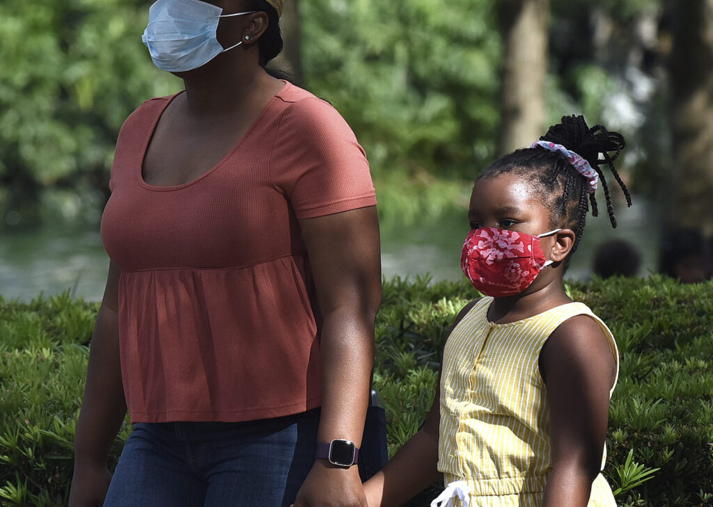Florida Passes New York in Total COVID-19 Cases – 25 Jul 2020 A child and her mother wearing face masks as a preventive measure walk at Lake Eola Park.