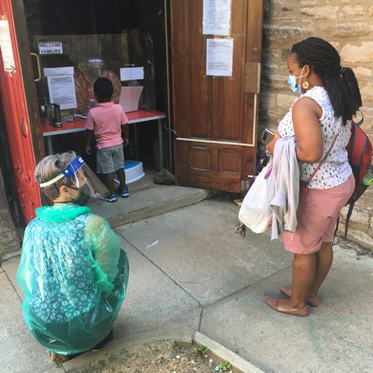 St. Mary's Nursery School director Traci Childress, in full hazmat gear, watches teacher Genevieve Abaara as she drops off her son. (Courtesy of the Notebook)