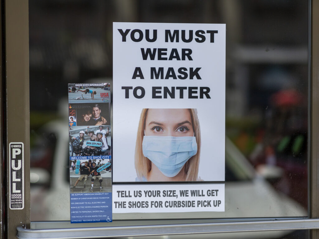 Masks are required for entry to a shoe store in Glendale, Calif. Most people follow social distancing and guidelines to wear masks when they enter retail stores and restaurants, but some customers don't comply.