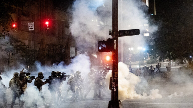 Federal agents use crowd control munitions to disperse Black Lives Matter protesters near the Mark O. Hatfield United States Courthouse on Monday, July 20, 2020, in Portland, Ore. Officers used teargas and projectiles to move the crowd after some protesters tore down a fence fronting the courthouse. (AP Photo/Noah Berger)