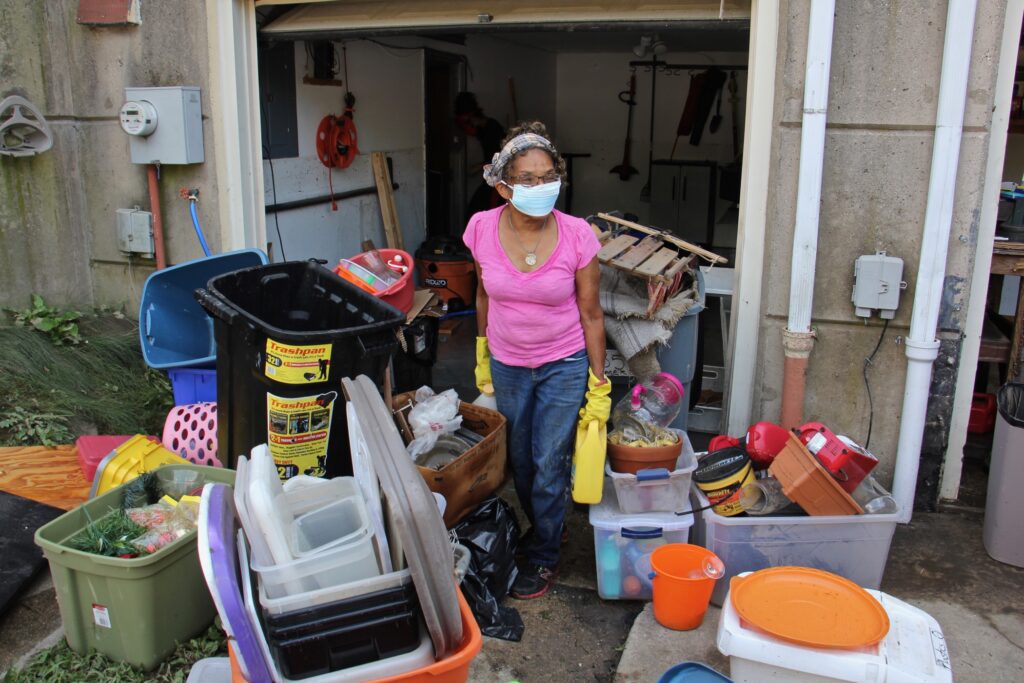 Yvette Palmer, 70, carries belongings out of the flooded first floor of her Eastwick home. (Emma Lee/WHYY)