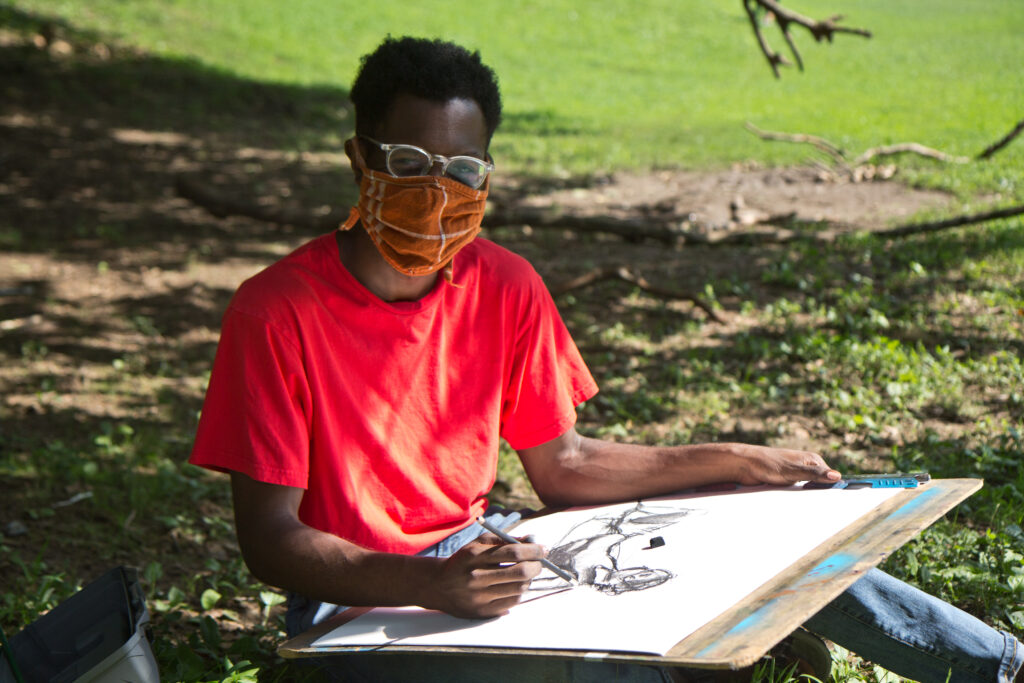 2020 8 14 k paynter ncik moncy Nick Moncy, a young Black man, draws outside in a West Philadelphia park while wearing a mask