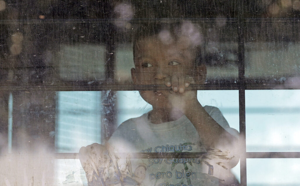 An immigrant child looks out from a U.S. Border Patrol bus as protesters block the street outside the U.S. Border Patrol Central Processing Center Saturday, June 23, 2018, in McAllen, Texas. (AP Photo/David J. Phillip)