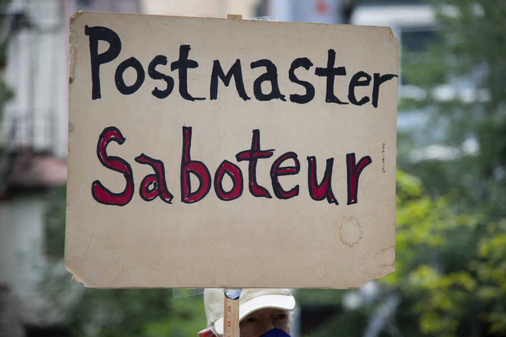 DC: Protests Against Trump and Postmaster General A protester holding a sign waits to march to the residence of Postmaster General Louis DeJoy - a major Republican donor who President Trump recently nominated to run the United States Postal Service (USPS) despite concerns about conflicts of interest and lack of experience - to demonstrate against Dejoy's changes to the USPS, which many say are acts of sabotage to increase Trump's chances in a mostly vote-by-mail election in Washington, D.C., on August 15, 2020, amid the coronavirus pandemic. DeJoy reportedly has invested tens of millions of dollars in direct USPS competitors, and recently he has enacted many changes at the USPS that postal worker unions and election experts say will make the election difficult or impossible to carry out effectively. (Graeme Sloan/Sipa USA)(Sipa via AP Images)