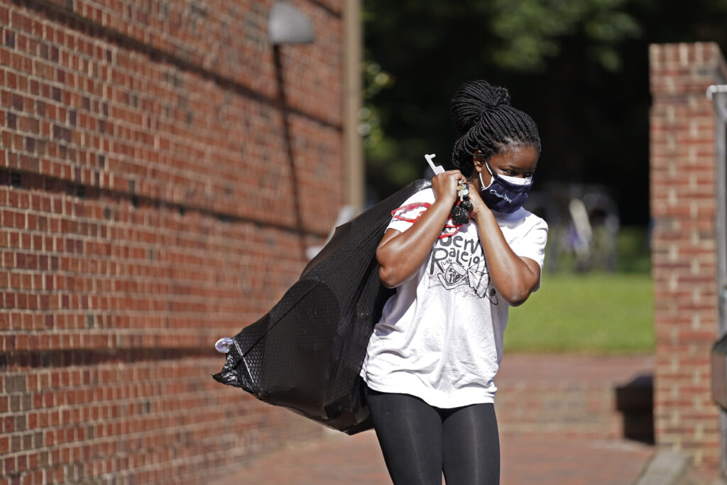 Virus Outbreak Universities Oyeronke Popoola, a 17-year-old freshman from Raleigh, carries some of her belongings as she and other students leave campus following a cluster of COVID-19 cases at The University of North Carolina in Chapel Hill, N.C., Tuesday, Aug. 18, 2020. (AP Photo/Gerry Broome)