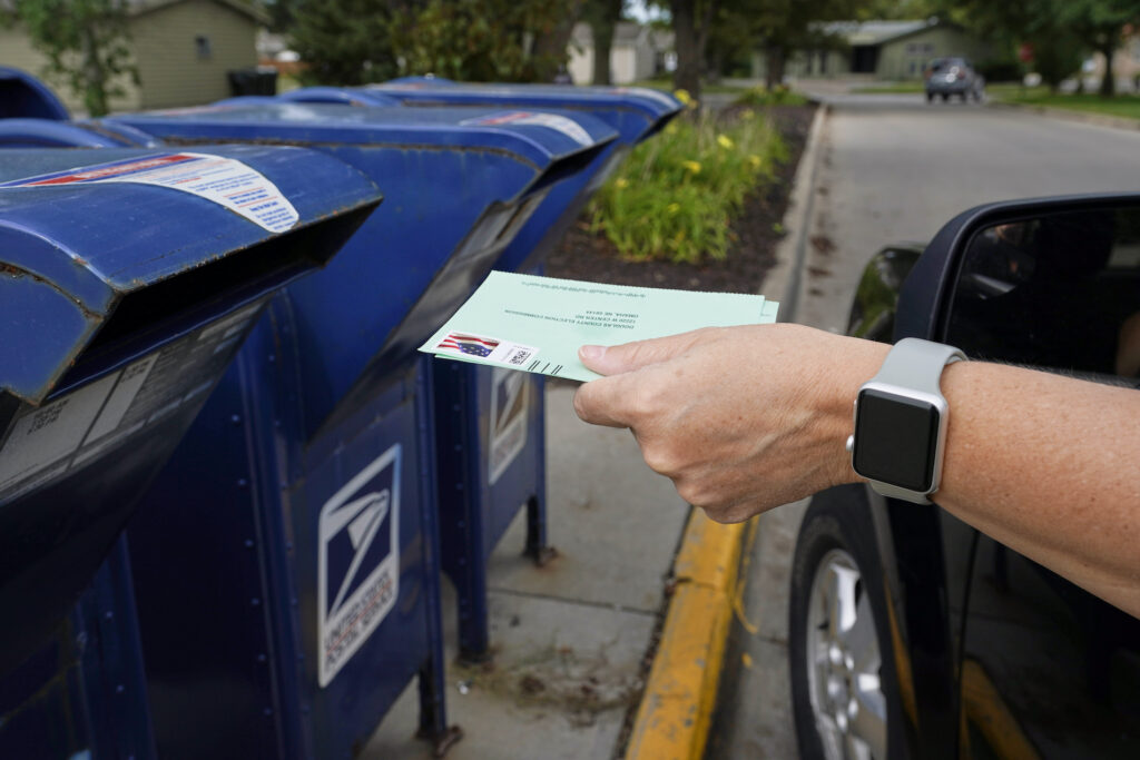Election 2020 Postal Service A person drops into a mail box applications for mail-in ballots