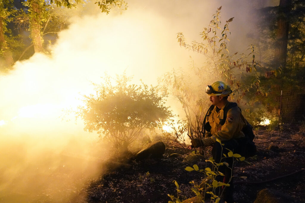 Jeremy Damon Firefighter Jeremy Damon of the Nevada Yuba Placer Fire Dept. monitors a controlled burn in the backyard of a home in front of the advancing CZU August Lightning Complex Fire Friday, Aug. 21, 2020, in Boulder Creek, Calif. (AP Photo/Marcio Jose Sanchez)