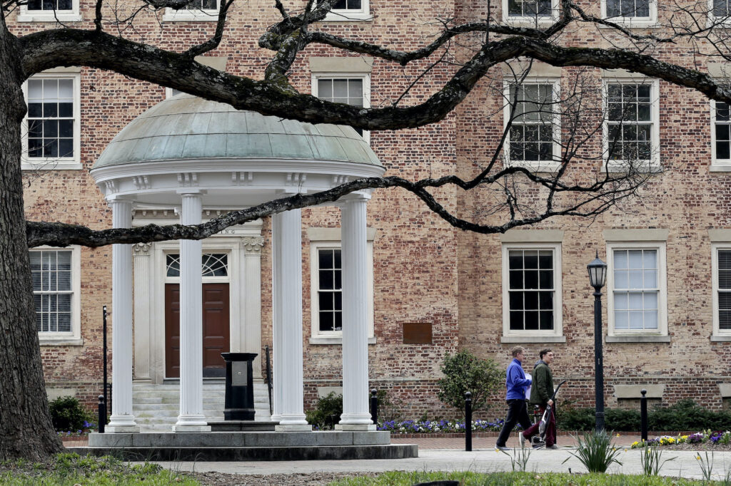 In this Wednesday, March 18, 2020, file photo, people remove belongings on campus at the University of North Carolina in Chapel Hill, N.C., amid the coronavirus pandemic. (AP Photo/Gerry Broome)