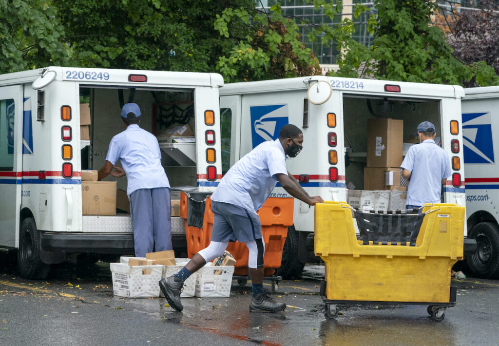 Letter carriers load mail trucks for deliveries at a U.S. Postal Service facility Letter carriers load mail trucks for deliveries at a U.S. Postal Service facility