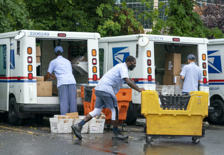 Letter carriers load mail trucks for deliveries at a U.S. Postal Service facility