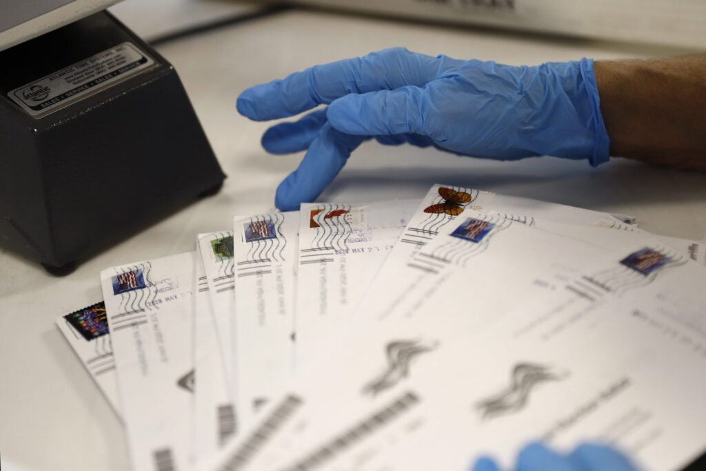 A worker processes mail-in ballots