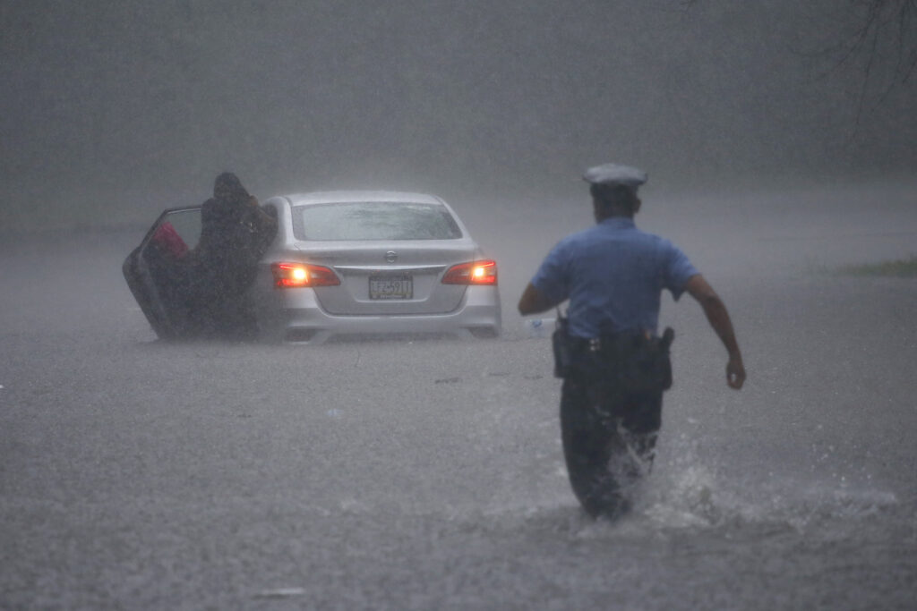 A Philadelphia police officer rushes to help a stranded motorist during Tropical Storm Isaias