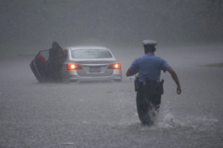 A Philadelphia police officer rushes to help a stranded motorist during Tropical Storm Isaias