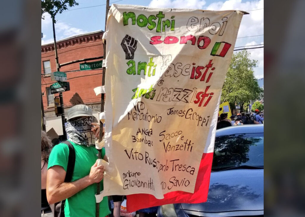 EbPBliUWkAQAS4w A protester carries a sign in Italian that reads