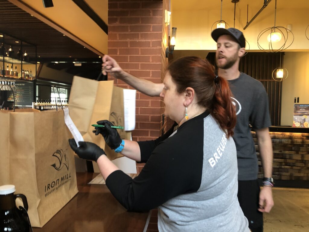 IMG_6565 Moriah Guise and Dustin Mitchell check takeout orders at Iron Hill Brewery. (Cris Barrish/WHYY)