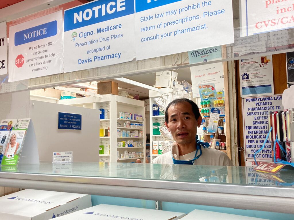 Image from iOS (135) Pharmacist Steven Nguyen works at Davis Pharmacy on Baltimore Ave. He’s been calling the US Postal Service’s line for days trying to track down customer packages (Hannah Chinn/WHYY)