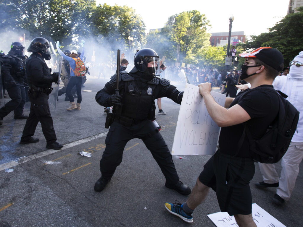 A law enforcement officer raises a baton and tear gas is fired during protests near the White House on June 1. A law enforcement officer raises a baton and tear gas is fired during protests near the White House on June 1. (Jose Luis Magana/AFP via Getty Images)