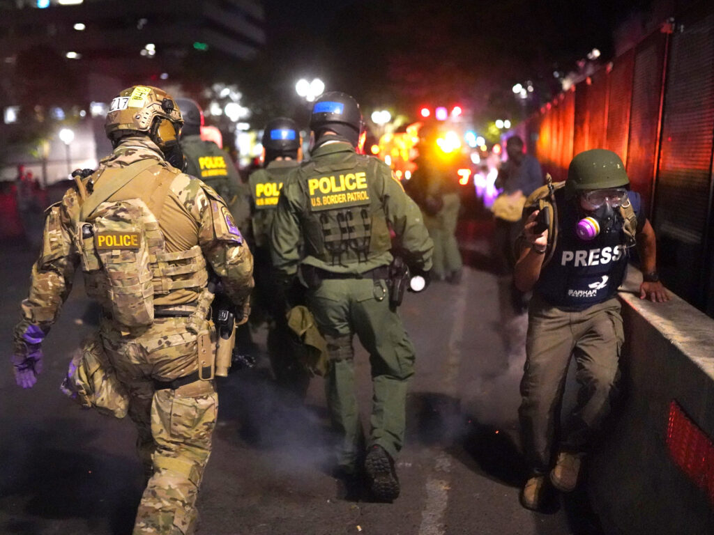 A journalist runs past federal officers after during a protest against racial injustice in front of the Mark O. Hatfield U.S. Courthouse on July 30, 2020 in Portland, Ore. A journalist runs past federal officers after during a protest against racial injustice in front of the Mark O. Hatfield U.S. Courthouse on July 30, 2020 in Portland, Ore.
