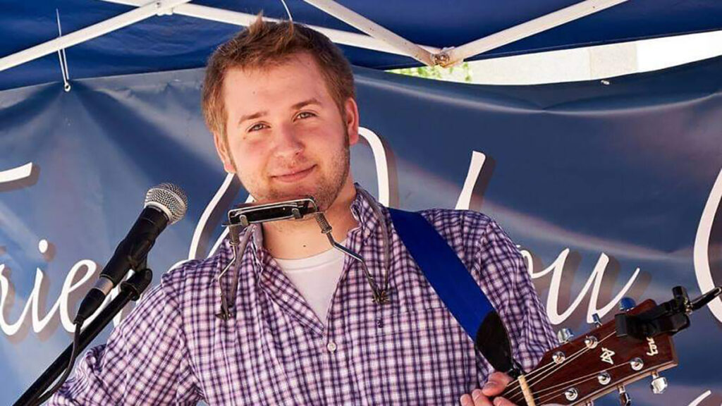 jordan16x9 Musician Jordan Bickhart with a harmonica and guitar