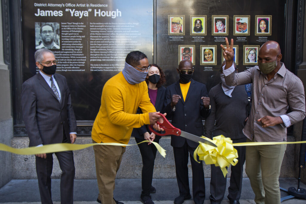 2020 9 30 k paynter DA artist-in-residence-7 James “Yaya” Hough, first-ever artist-in-residence at the Philadelphia District Attorney’s Office, cuts a ribbon with DA Larry Krasner (left), Mural Arts' Jane Golden, (third from left), Michael “Smokey” Wilson, (third from right) and boxing champion Bernard Hopkins (right). (Kimberly Paynter/WHYY)