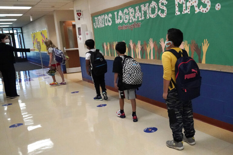 Students physically distance as they walk to their classroom