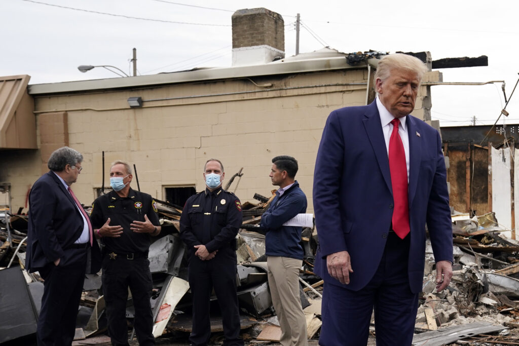 Donald Trump President Donald Trump turns around after talking with law enforcement officials Tuesday, Sept. 1, 2020, as he tours an area damaged during demonstrations after a police officer shot Jacob Blake in Kenosha, Wis. At left, Attorney General William Barr and acting Homeland Security Secretary Chad Wolf talk with police officers. (AP Photo/Evan Vucci)