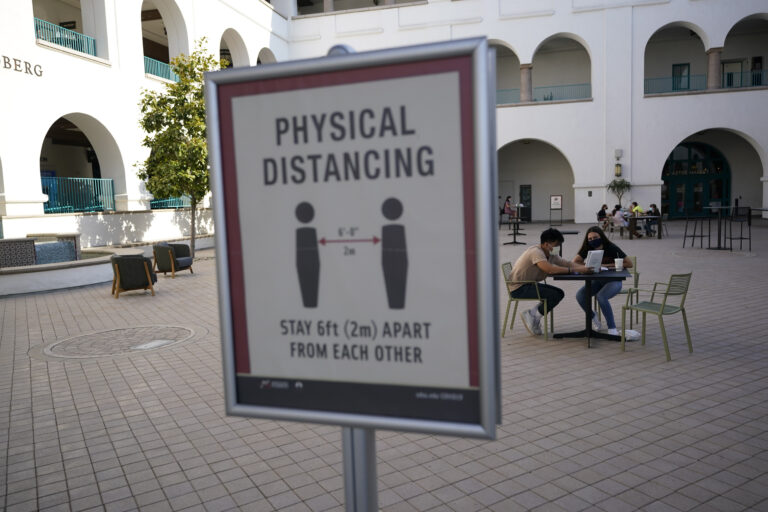 People sit at tables at San Diego State University Wednesday, Sept. 2, 2020, in San Diego. San Diego State University on Wednesday halted in-person classes for a month after dozens of students were infected with the coronavirus. (AP Photo/Gregory Bull)