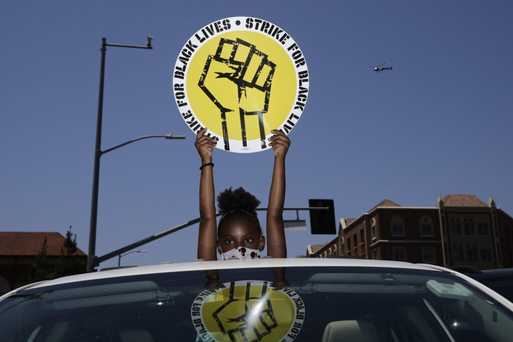 Racial Injustice Labor Unions In this July 20, 2020, file photo, Audrey Reed, 8, holds up a sing through the sunroof of a car during a rally in Los Angeles. Ahead of Labor Day, major U.S. labor unions say they are considering work stoppages in support of the Black Lives Matter movement. (AP Photo/Jae C. Hong)