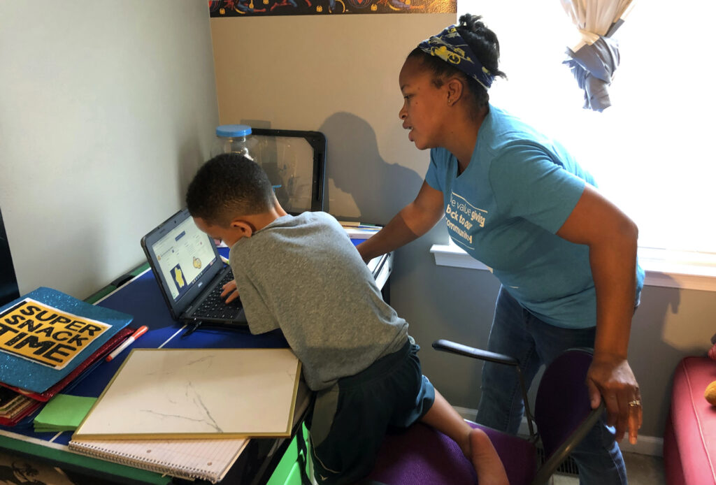 Virus Outbreak Schools Tiffany Shelton helps her 7-year-old son, P.J. Shelton, a second-grader, during an online class at their home in Norristown, Pa., on Thursday, Sept. 3, 2020. (AP Photo/Michael Rubinkam)