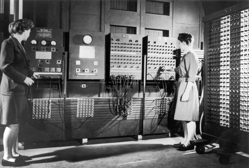Two_women_operating_ENIAC_(full_resolution) Two women operating the ENIAC's main control panel while the machine was still located at the Moore School. Left: Betty Jennings (Mrs. Bartik) Right: Frances Bilas (Mrs. Spence) setting up the ENIAC. (United States Army/Public domain)