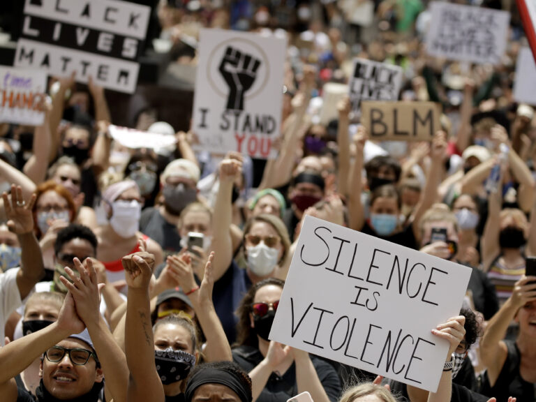 In this June 5 photo, demonstrators in downtown Kansas City, Mo., hold signs during a rally to protest the death of George Floyd. President Trump has ordered the federal government to stop critical race theory trainings. (Charlie Riedel/AP Photo)