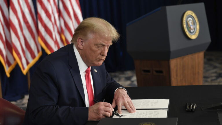President Trump signs one of four executive orders addressing the economic fallout from the pandemic in Bedminster, N.J., on Aug. 8. The Trump administration has given employers the option to stop collecting payroll taxes, but workers may have to repay the money next year.