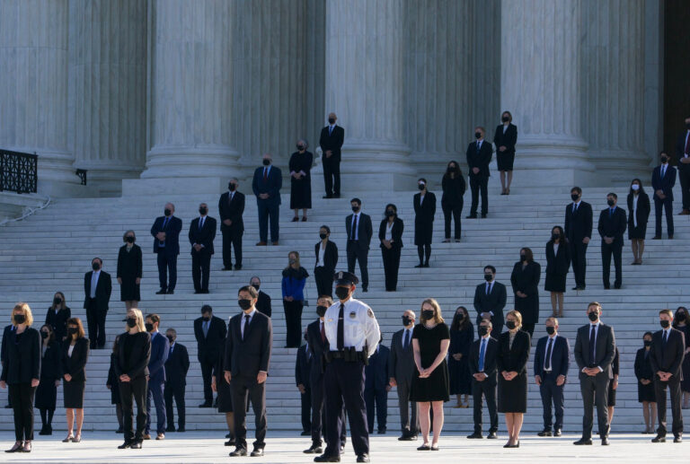 Former law clerks for Justice Ruth Bader Ginsburg stand on the steps of the Supreme Court as they await the arrival of the casket of Ginsburg on Wednesday. (Claire Harbage/NPR)