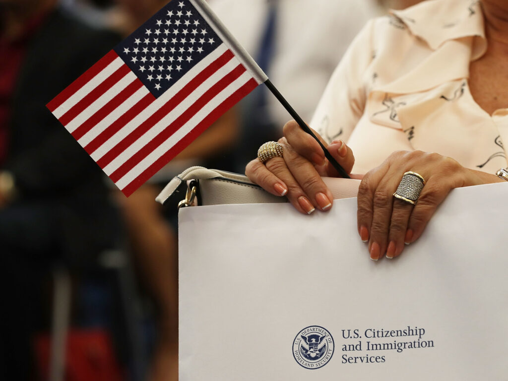 An attendee holds an American flag at a U.S. Citizenship & Immigration Services naturalization ceremony in Miami, Fla. in Aug. 2018. The Trump administration is considering expanding its collection of biometric data as part of the immigration process. An attendee holds an American flag at a U.S. Citizenship & Immigration Services naturalization ceremony